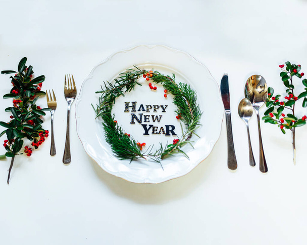 Happy New Year porcelain plate with Christmas wreath. Party decoration, flat lay, top view. Empty space. Restaurant menu concept. Isolated on white background. Winter holidays background. - Fotoğraf, Görsel