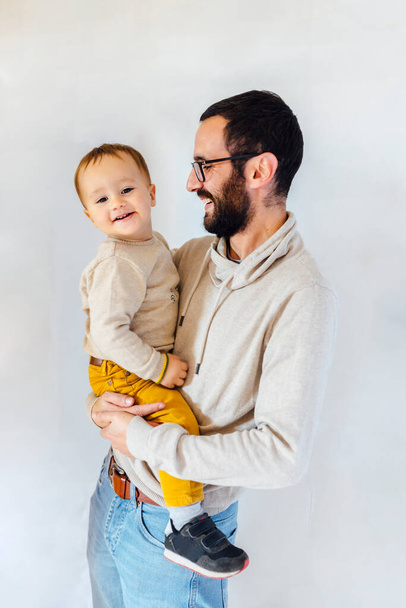 Junger Vater mit seinem Sohn im Arm auf weißem Hintergrund. Vater-Baby-Konzept. - Foto, Bild
