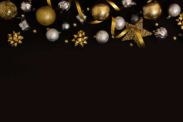 Christmas background with fir branches, gold decorations and pine cones on a black table. Flat lay. top view with copy space. High quality photo - Foto, immagini