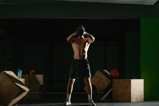 Sağlıklı bir fitness oyuncusunun yüksek kontrastlı fotoğrafı kettlebell kullanıyor. - Fotoğraf, Görsel
