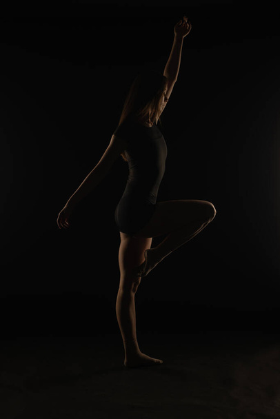Joven bailarina en el estudio está sosteniendo una buena postura mientras posa, silueta - Foto, Imagen