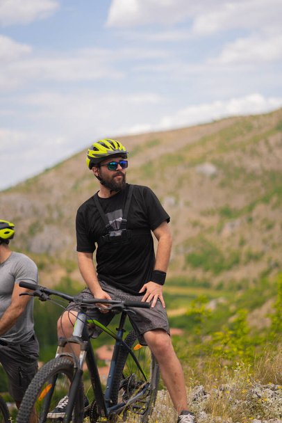 Portret dorosłego rowerzysty rozglądającego się po górach i cieszącego się widokiem podczas przerwy - Zdjęcie, obraz