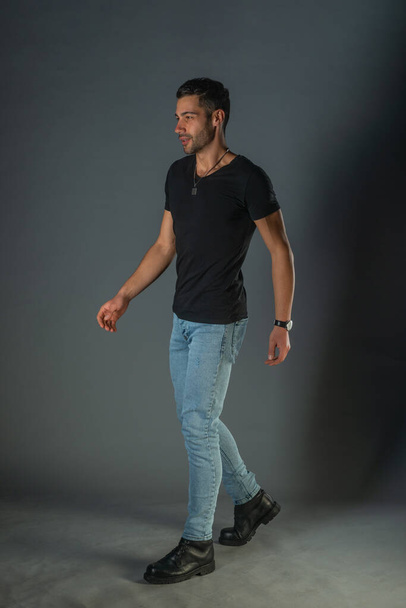 Photoshoot studio d'un bel homme posant en jeans et chemise noire - Photo, image