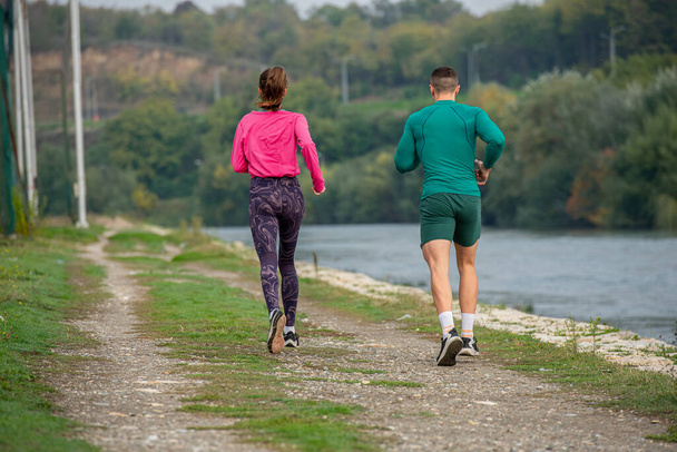 İnanılmaz ve sportif bir çift sabah nehir kenarında birlikte koşuyor. - Fotoğraf, Görsel