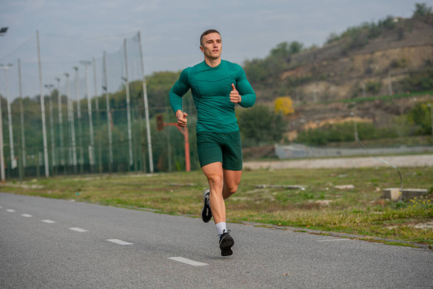 Atractivo y guapo chico fuerte está haciendo una mañana corriendo antes de su entrenamiento - Foto, imagen