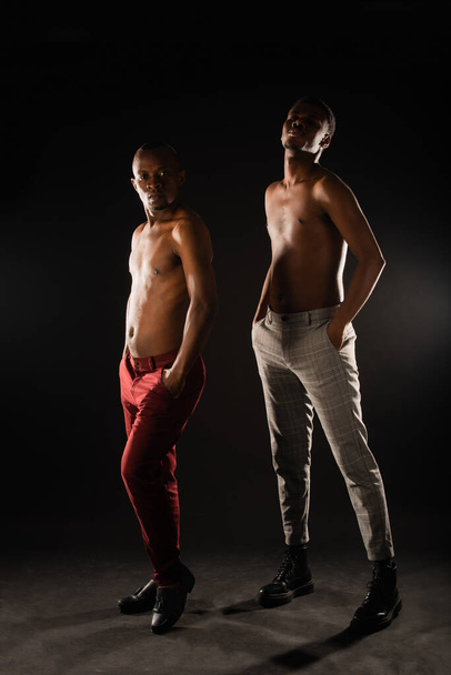 Дві топлес чорні чоловіки позують разом на темному тлі
 - Фото, зображення