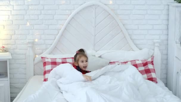 Children in pajamas jump, play pranks and have fun in their parents' bed before going to bed. Girls can't sleep on Christmas Eve looking forward to gifts from Santa. Xmas  - Footage, Video