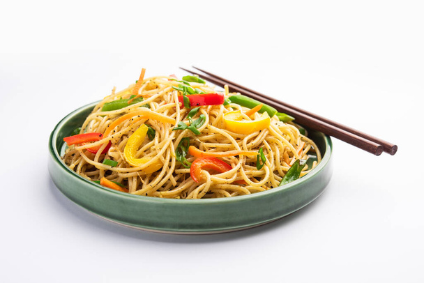 Schezwan麺またはSzechwan野菜客家麺やチャウミンは、木製の箸でボウルやプレートで提供される人気のインド・中国のレシピです。 - 写真・画像
