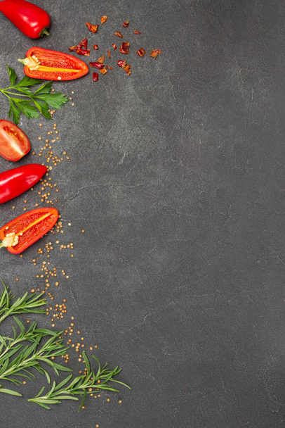 Sliced red peppers and sprigs of rosemary along edge of background. Food Menu concept. Food background. Flat lay. Copy space - Foto, afbeelding