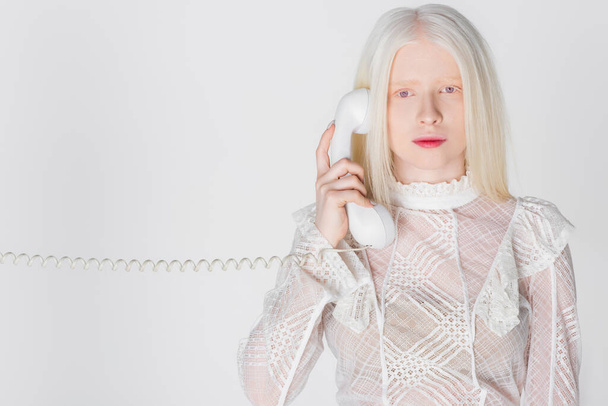 Mujer albina hablando por teléfono y mirando a la cámara aislada en blanco  - Foto, Imagen