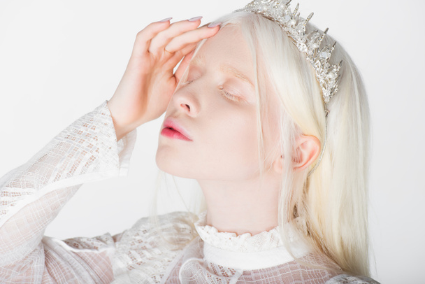 Junge Albino-Frau in Krone mit Edelsteinen, die Augen auf Weiß geschlossen - Foto, Bild