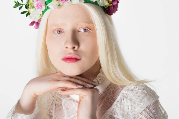 Porträt einer hübschen Albino-Frau im Kranz mit Blumen, die isoliert auf weiß in die Kamera blickt - Foto, Bild