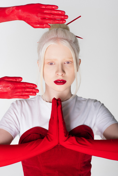 Κομψό αλμπίνο μοντέλο σε γάντια που δείχνει τα χέρια προσευχή κοντά γυναικεία χέρια σε χρώμα που απομονώνονται σε λευκό - Φωτογραφία, εικόνα