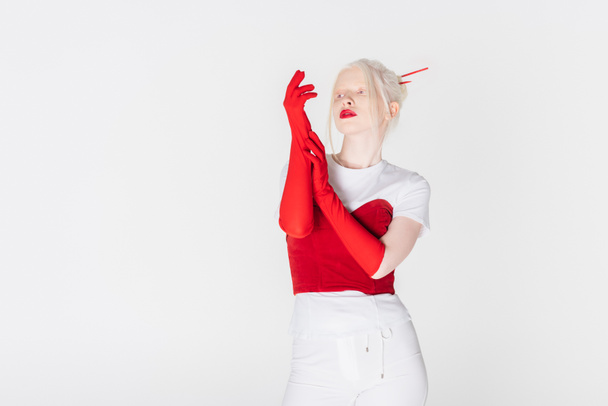 Стильная альбиноса женщина в красных перчатках смотрит в сторону изолированы на белом - Фото, изображение
