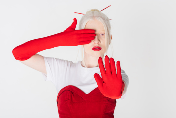 Modelo albino borroso en guantes rojos mostrando señal de stop aislado en blanco - Foto, imagen