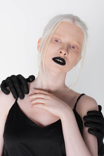 Male hands in black paint hugging albino model isolated on white - Fotó, kép