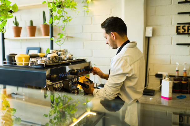 Vue arrière d'un barista masculin versant une tasse de café avec une machine à café et servant des clients - Photo, image