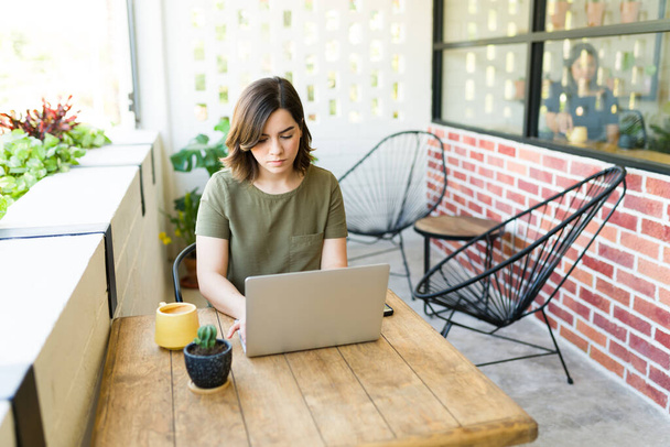 Elfoglalt nő gépel a laptopon, és egy kávézóban dolgozik. Szabadúszó munkás kávét iszik  - Fotó, kép