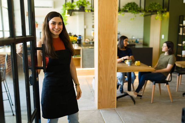 Žena obchodní majitel otevírá dveře a usmívá se zákazníky v kavárně - Fotografie, Obrázek