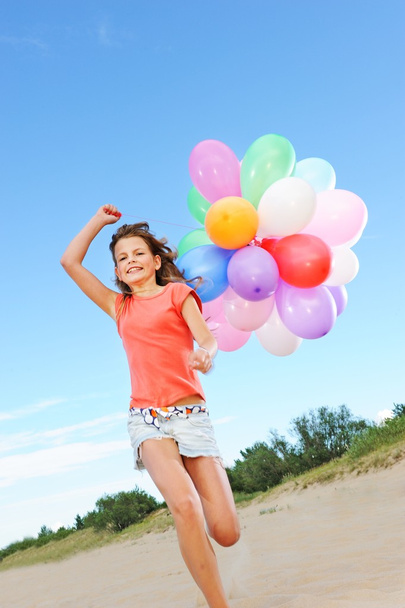 Happy girl with balloons running on the beach - Photo, Image