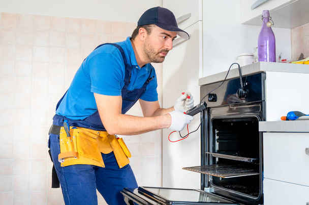 One repairman fixing malfunctioning kitchen oven problem - Fotoğraf, Görsel