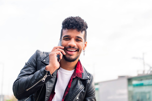 young latin man smiling happy while talking on the phone, concept of technology and urban lifestyle - Fotoğraf, Görsel
