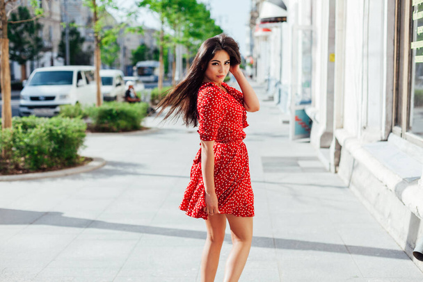 beautiful woman in a summer red dress walks down the street - Photo, Image