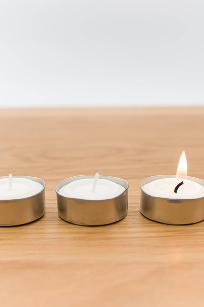 row of white scented wax tea lights on a wooden tabletop with copy space - Photo, Image