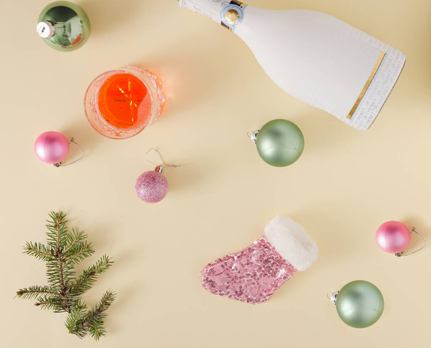 Pose plate créative du Nouvel An avec bouteille de champagne blanche et or et décoration de Noël sur fond jaune pastel. - Photo, image