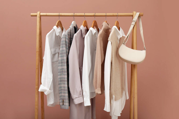 Rack with different stylish clothes and bag on pale pink background - Fotografie, Obrázek