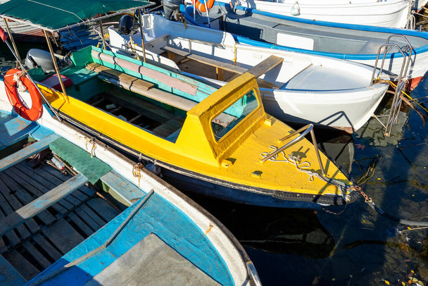 明るい晴れた日に漁師村マリーナ澄んだ水の湾に係留された多くの小さな古い木製のヴィンテージカラフルな明るい漁船の行。伝統的なレトロな船を背景にした海港 - 写真・画像