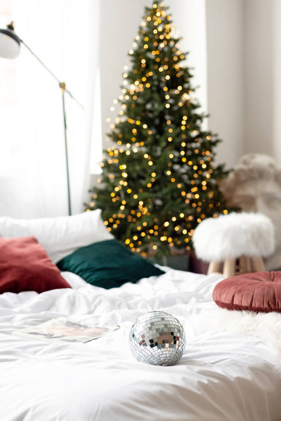 Різдвяний декор. Спальня в світлих тонах з великим ліжком. Інтер'єр прикрашений гірляндами, різдвяними вінками і новорічною ялинкою в сучасному стилі. М'який вибірковий фокус
. - Фото, зображення