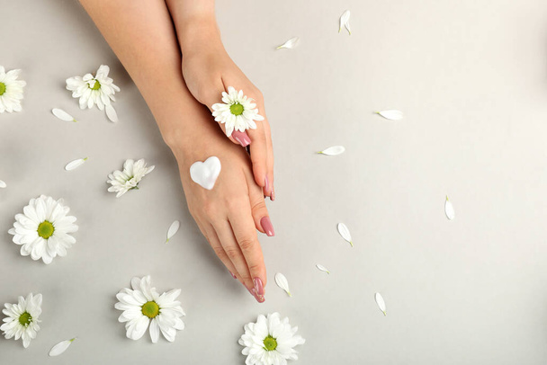Koncepcja pielęgnacji dłoni na szarym tle z kwiatami - Zdjęcie, obraz
