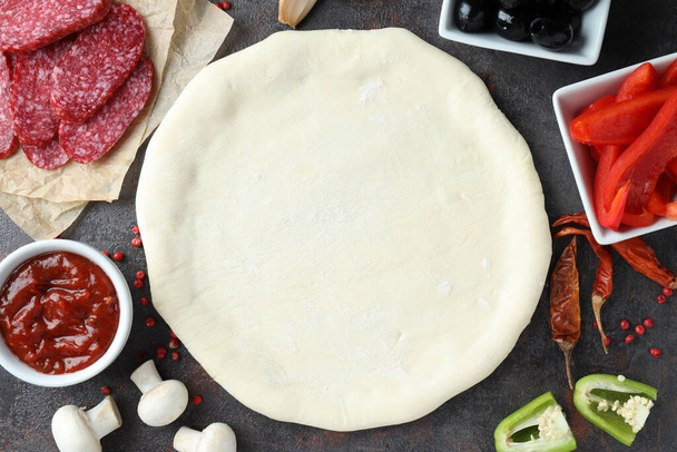 Концепция приготовления пиццы на темном текстурированном фоне - Фото, изображение