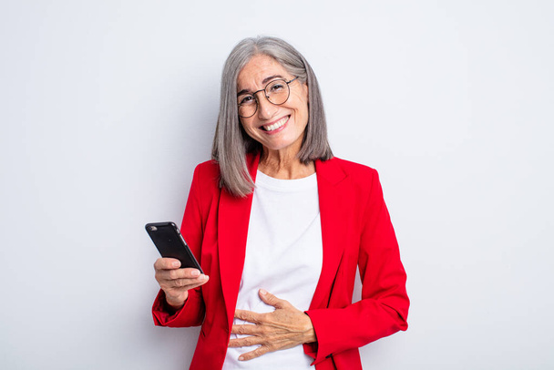 senior pretty woman laughing out loud at some hilarious joke.. business and phone concept - Фото, изображение