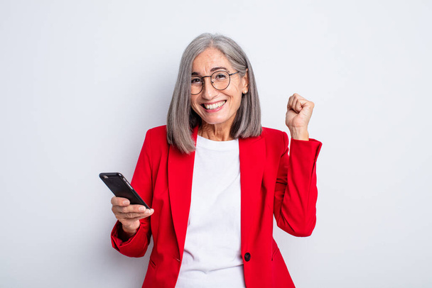 senior pretty woman feeling shocked,laughing and celebrating success.. business and phone concept - 写真・画像