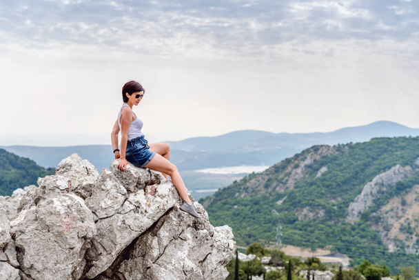 Νεαρή γυναίκα σε φόντο βουνών - Φωτογραφία, εικόνα