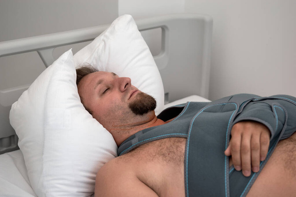 Homem com cateter-conta-gotas deitado na cama na enfermaria do hospital. Fractura elástica no ombro. Emergência - Foto, Imagem