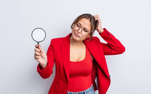 hispanic pretty woman smiling happily and daydreaming or doubting. magnifying glass concept - Photo, image