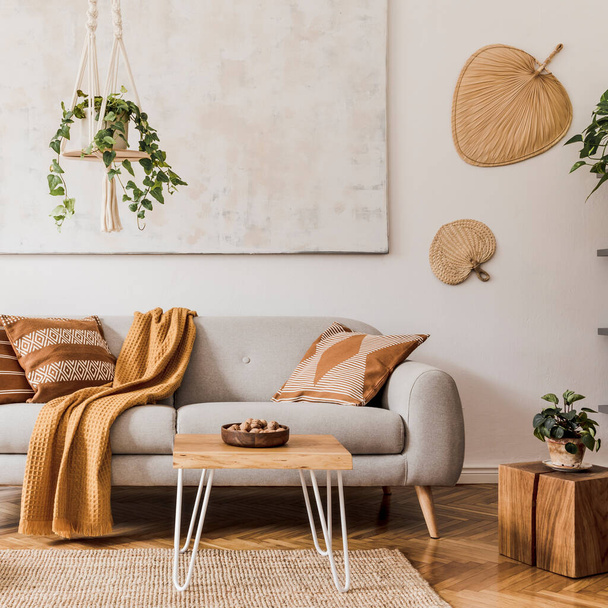Stylish composition of creative and cozy living room interior with grey sofa, coffee table, plants, carpet and beautiful accessories. White walls and parquet floor. - Foto, immagini