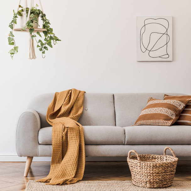 Stylish composition of creative and cozy living room interior with grey sofa, plants, carpet and beautiful accessories. White walls and parquet floor. - Valokuva, kuva