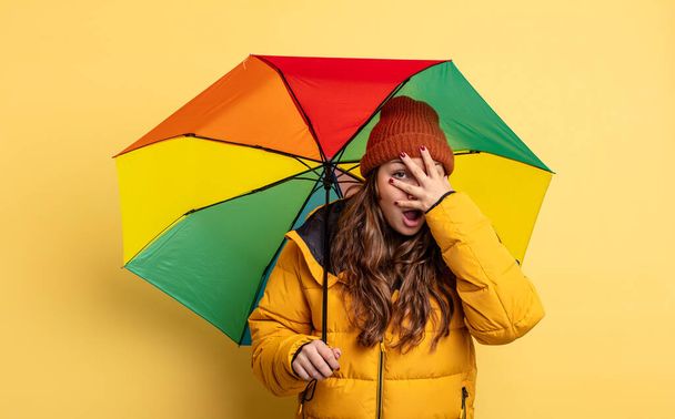 hispanic pretty woman looking shocked, scared or terrified, covering face with hand. umbrella concept - Photo, image