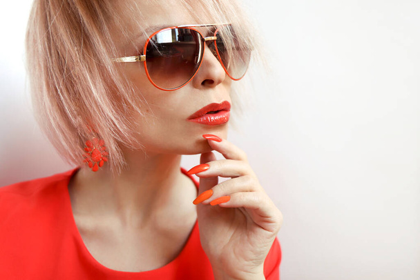 Orange makeup and manicure on a blonde with sunglasses. - Fotoğraf, Görsel