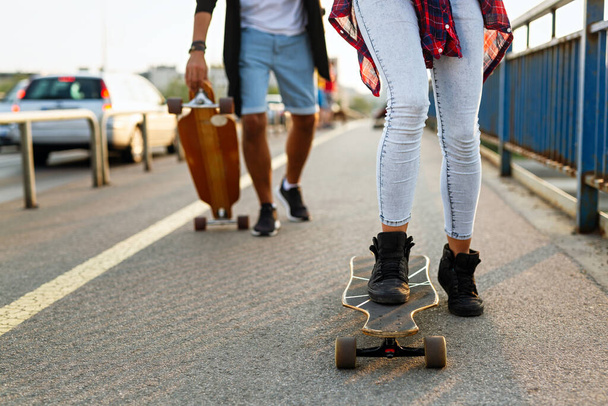 Group of happy friends hang out together and enjoying skateboard outdoors. - Fotó, kép