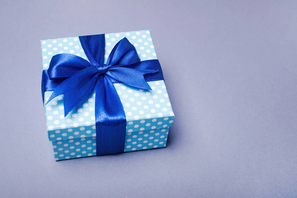 Blue gift box with a bow on a gray background. Holiday greeting card. New Year and Christmas concept. - Photo, image