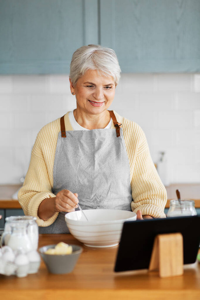 woman with tablet computer cooking food on kitchen - Foto, imagen