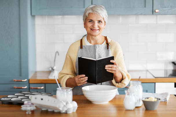 šťastná žena s kuchařkou vaření jídlo na kuchyni - Fotografie, Obrázek