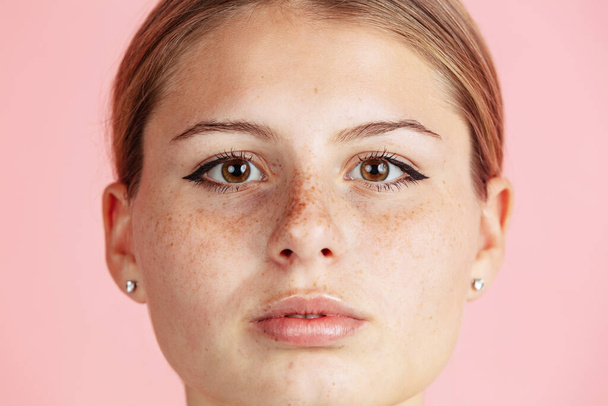 Close-up young girls face with cute freckles isolated over pink studio background. Facial expression concept - Foto, Imagem