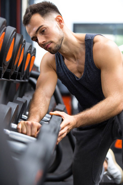 weightlifter choosing dumbbell for training session - Fotó, kép
