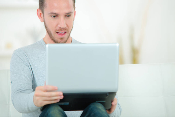 young man with laptop on sofa in the room - Foto, imagen